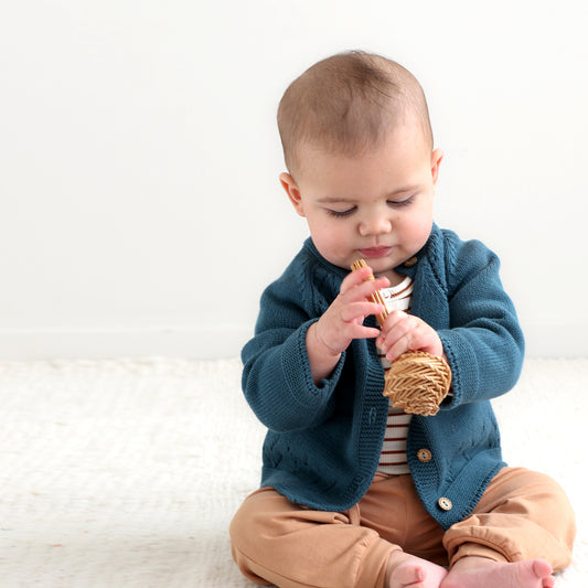 Baby boy playing with wooden toy while wearing Adison Knit Cardigan, striped bodysuit and marley pants by Burrow and Be