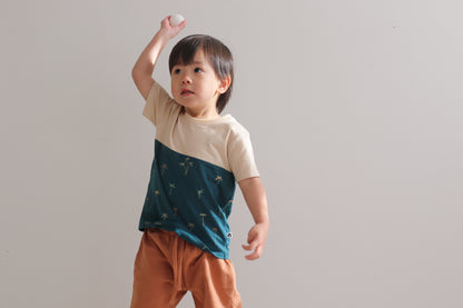 Boy holding a ball, standing in front of a white wall while wearing Palm Block T-Shirt with Leo Shorts in Tan, both designed by Burrow and Be