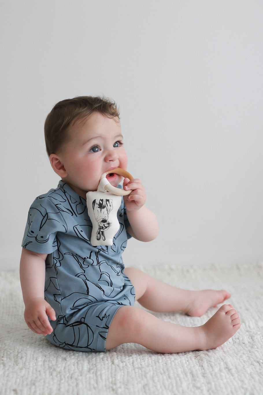 Baby biting maple ring fabric teether and wearing Giant Bugs Alex Romper from Burrow and Be