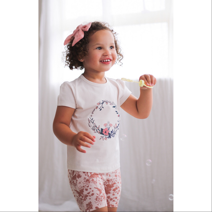 Girl posing at the camera while wearing Fairy Wreath T-shirt and Flower Splash Bike Shorts, both designed by Burrow and Be