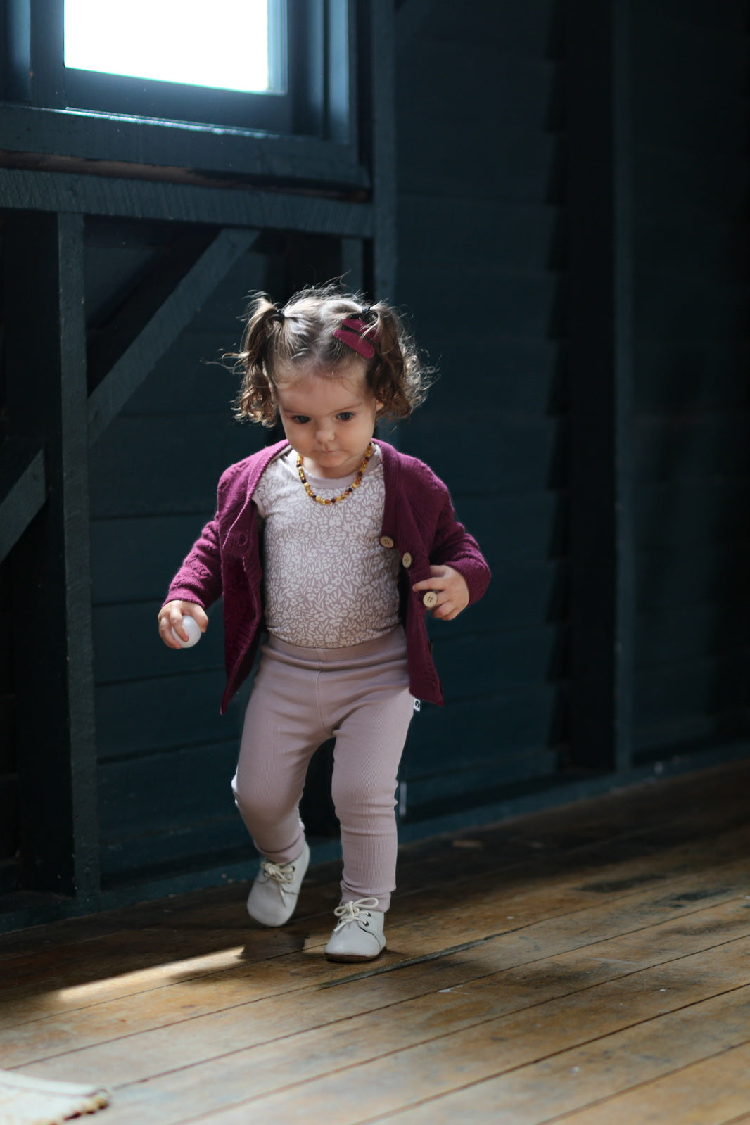 Girl in a barn wearing Addison Knit Cardigan wearing a floral bodysuit and Essential Derby Rib Leggings - Lavender, all designed by Burrow and Be