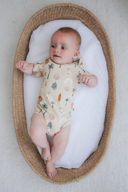 Baby in Moses Basket wearing Jungle Stamp Bodysuit, designed by Burrow and Be