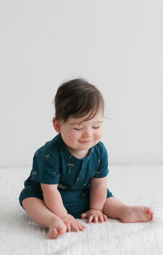 Baby staring at the floor while wearing Palm Alex Romper from Burrow and Be