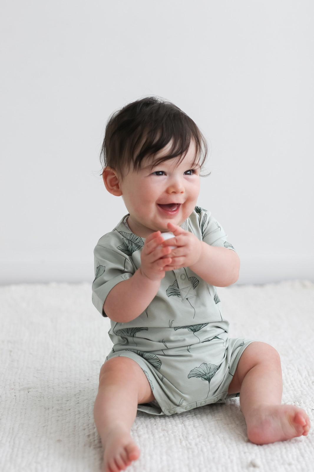 Baby laughing while wearing Burrow and Be Ginkgo Alex Romper