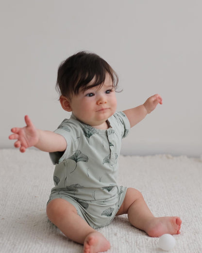 Baby looking for a hug while wearing Ginkgo Alex Romper from Burrow and Be