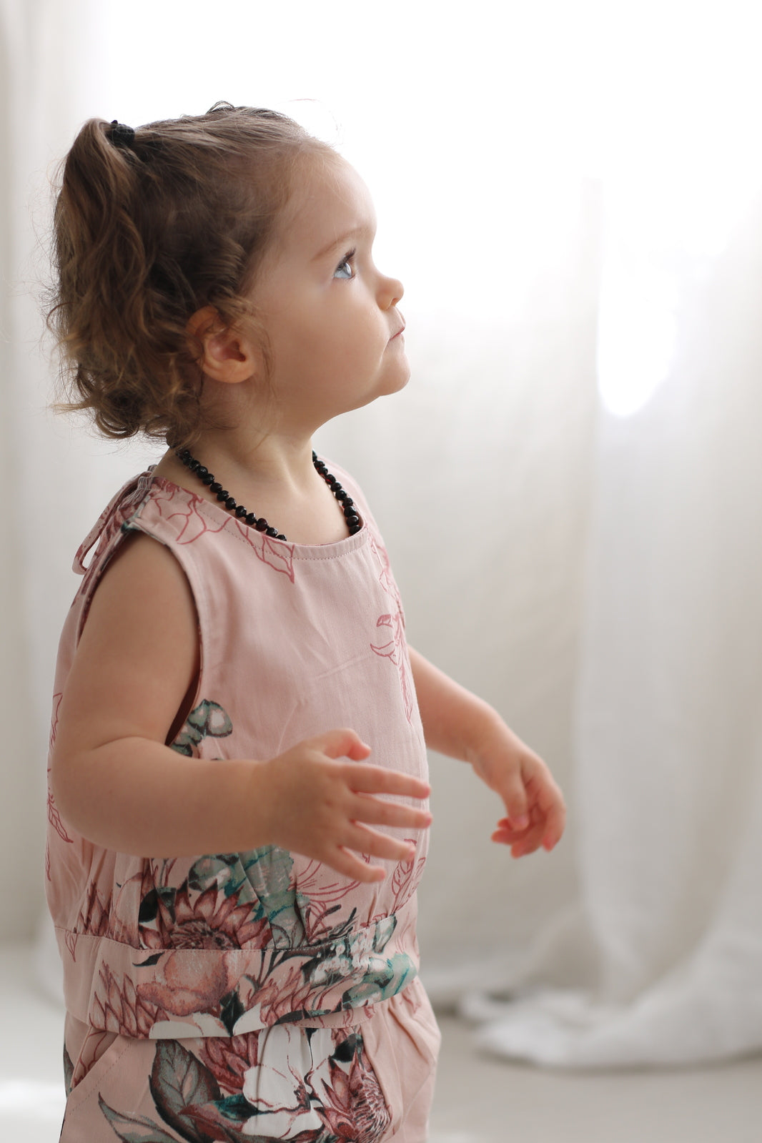 Baby girl looking to the left while wearing Tropical Bouquet Singlet - Fleur and Tropical Bouquet Lyla Shorts - Fleur, both designed by Burrow and Be