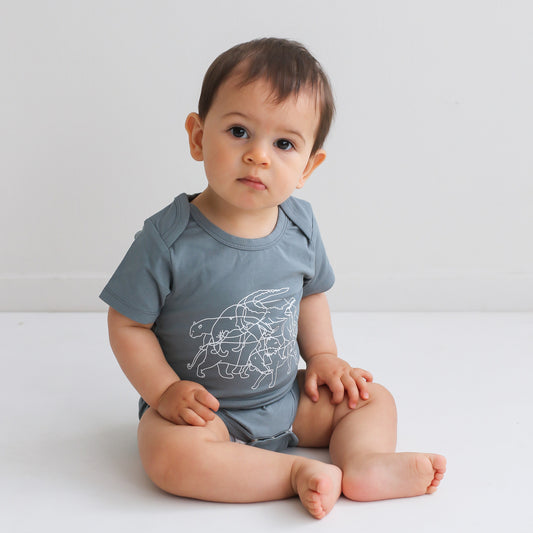 Baby boy sitting on a white floor against a white background wearing Lost on Storm Bodysuit, designed by Burrow and Be